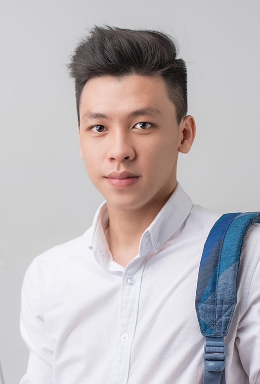 Happy casual asian male student using laptop isolated on a gray background